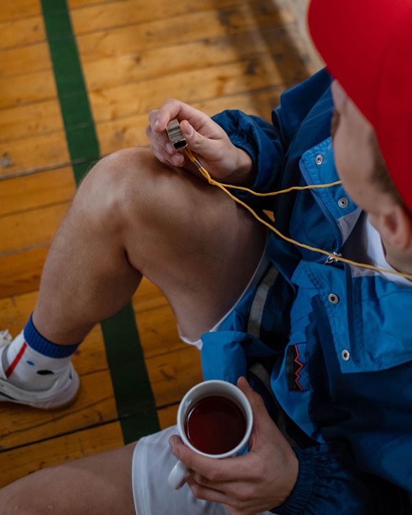 A coach holding a whistle and a mug of tea